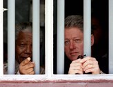 Nelson Mandela acompanhado de Bill Clinton, quando este era presidente dos EUA, numa visita à cela onde esteve preso durante 17 anos.