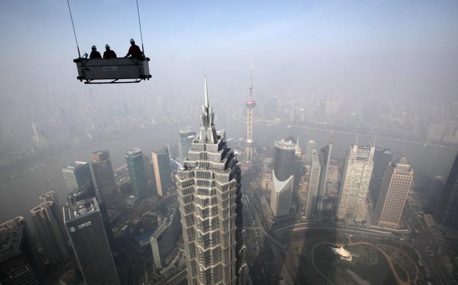 Trabalhadores numa plataforma suspensa preparados para limpar janelas do Shanghai World Financial Center, em Xangai. Fotografia: Tomohiro Ohsumi