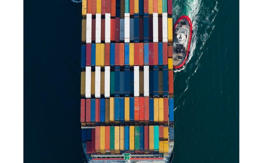 Barcos rebocadores ajudam a guiar um cargueiro com contentores a aproximar-se do porto de Long Beach, na Califórnia. Fotografia de Tim Rue