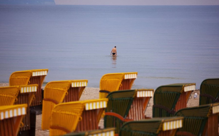 Um banhista desfruta do Mar Báltico, na ilha alemã de Ruegen, em Agosto de 2013, tendo como pano de fundo cadeiras de praia vazias. Fotografia de Krisztian Bocsi