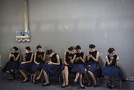 Anfitriãs da exposição a utilizar os seus “smartphones” durante o China International Automobile Exhibition, em Guangzhou.