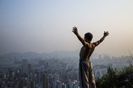 Um homem faz alongamentos observando os edifícios de Hong Kong, na China.
