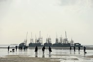 Funcionários caminham para as jangadas de madeira numa praia da costa da ilha de Bangska, na Indonésia. A ilha de Bangka produz 90% do estanho na Indonésia.