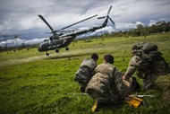 Agentes da polícia observam enquanto um helicóptero que é carregado com abastecimentos para fazer uma incursão a um campo de minas de ouro ilegal dentro da reserva nacional da Amazónia, no Perú.