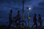 Pessoas passam por um poste de iluminação alimentado por energia solar em Dharnai, na Índia.