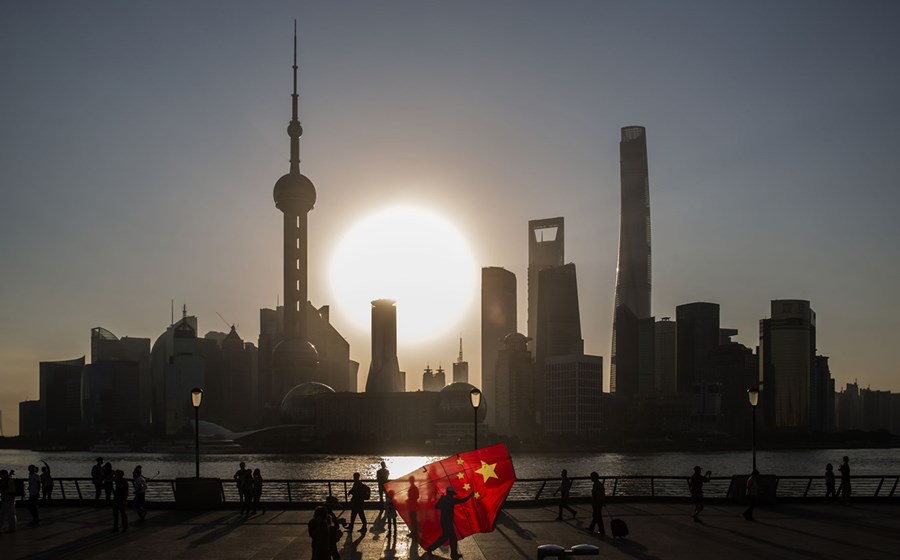 Um homem levando um papagaio de papel com a forma da bandeira nacional chinesa com os prédios do distrito financeiro de Lujiazui, em Xangai, na China, como pano de fundo.