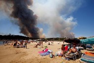 Uma nuvem de fumo devido a um incêncio de grandes proporções não afecta o dia de praia dos turistas em Bormes-les-Mimosas, França.