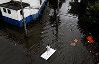 Um trabalhador usa uma tábua de madeira para escapar às cheias em São Paulo, no Brasil.