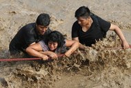 Dois homens socorrem uma mulher após um deslizamento de terras e inundações em Huachipa, no distrito de Lima, no Peru.
