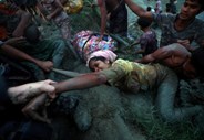 Fotógrafos ajudam uma refugiada Rohingya a sair de um rio perto da fronteira entre Myanmar e o Bangladesh.