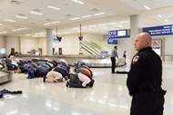 Várias pessoas param para rezar, durante um protesto num local de recolha de bagagens no aeroporto de Dallas, contra a ordem de proibição de concessão de vistos por parte de Donald Trump. 