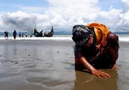 Uma mulher refugiada Rohingya, exausta, descansa na praia depois de atravessar de barco a fronteira entre Bangladesh e Myanmar, através da Baía de Bengala, em Shah Porir Dwip, no Bangladesh.