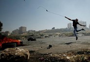 Um manifestante palestiniano lança pedras contra as tropas israelitas durante um protesto de apoio a prisioneiros em greve de fome nas prisões de Israel, na cidade de Ramallah, na Cisjordânia.