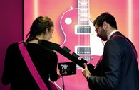 Visitantes tocam guitarra eléctrica através de um tablet da Huawei