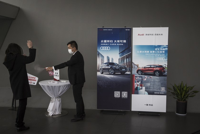 Colegas de trabalho desinfetam-se num stand da Audi na cidade chinesa