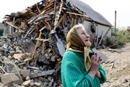 Mulher em fronte da sua casa destruída por um míssil na região de Donetsk.