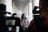 Pessoa sorri para câmaras em corredor com colunas