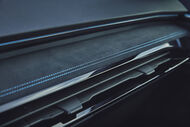 Detalhe do interior de um carro com costura azul e saídas de ar pretas