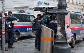 Polícia em Viena junto a carrinhas patrulha e edifícios