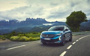 Carro azul numa estrada cénica com montanhas ao fundo