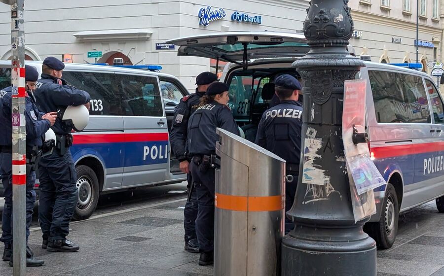 Polícia em Viena junto a carrinhas patrulha e edifícios
