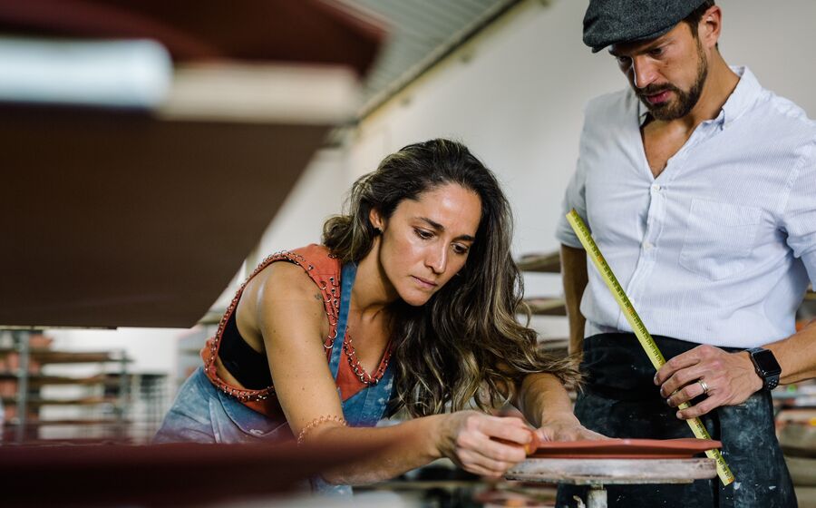 Gabi modela cerâmica com Alex no Studio Neves, criando pratos e chávenas.