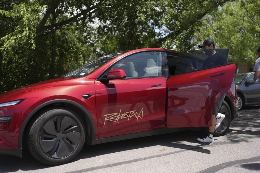 Tesla Robotaxi com passageiro a entrar no carro.