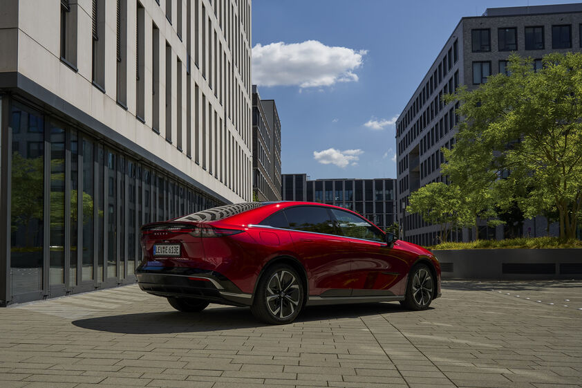 Carro elétrico vermelho da marca Fisker estacionado numa rua com edifícios