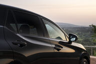 Lateral de um Lexus RZ preto com paisagem ao fundo