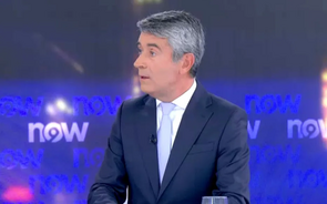 Apresentador num debate televisivo com o logótipo "now" no fundo