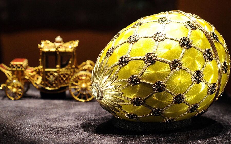 Um ovo Fabergé e uma carruagem dourada em exposição.