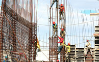 Trabalhadores da construção civil em obra com armaduras de aço.