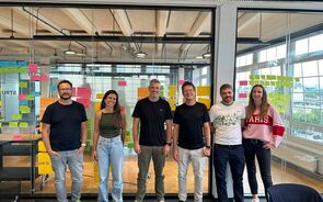 Grupo de pessoas posa para foto em escritório moderno com notas coloridas