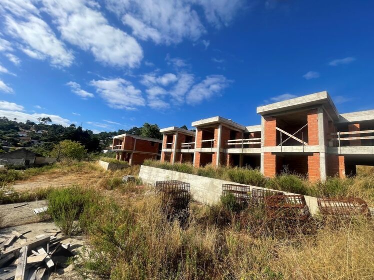 Construções inacabadas em área com vegetação sob céu azul
