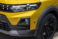 Detalhe de um carro amarelo com faróis e pneus pretos