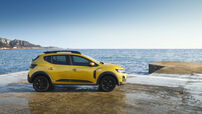 Um carro amarelo estacionado perto do mar num dia ensolarado