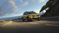Um Dacia Sandero Stepway amarelo circula por uma estrada costeira