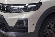 Detalhe da frente de um automóvel Dacia, destacando faróis e pneus