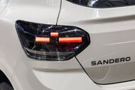Detalhe da traseira de um carro Sandero branco com uma luz traseira acesa