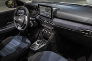 Interior do carro exibe ecrã de navegação, volante e assentos