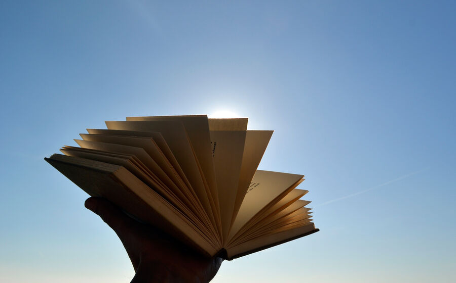 Um livro aberto em frente ao céu simboliza despedidas e o início de uma jornada pessoal