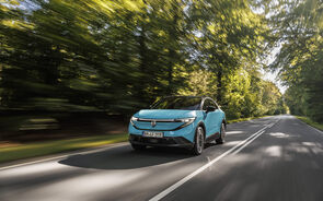 Carro elétrico azul na estrada, com árvores de cada lado