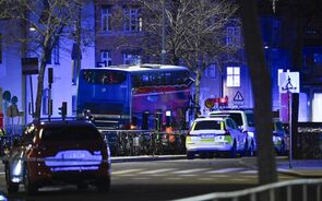 Autocarro e carros da polícia numa rua da cidade à noite