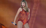 Taylor Swift atua num concerto com um body laranja brilhante e um microfone