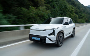 Kia EV5 circula numa estrada com paisagem verde