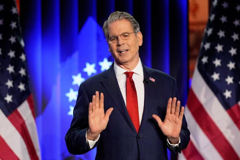 Secretário do Tesouro dos EUA discursa com bandeiras dos EUA ao fundo