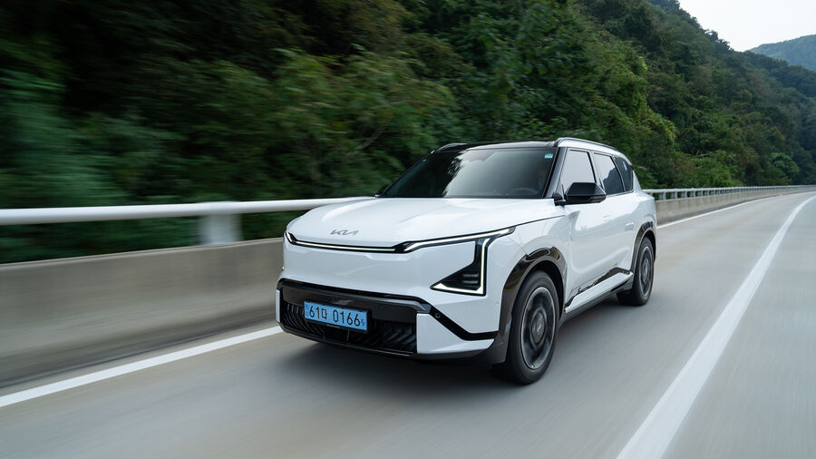 Kia EV5 circula numa estrada com paisagem verde