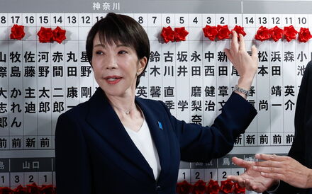 Sanae Takaichi coloca uma rosa vermelha de papel no nome de um deputado do seu partido eleito.