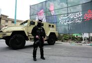 membros das forças de segurança iraniana junto a cartaz a homenagear o falecido líder supremo do Irão.