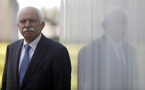 Retrato de Cavaco Silva, com fato e gravata, refletido num vidro